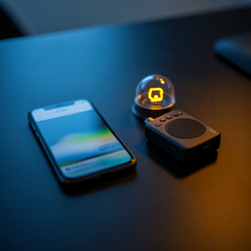 Smartphone posé près d’un enregistreur audio et d’une icône de notification lumineuse, évoquant la surveillance numérique et les avis en ligne.